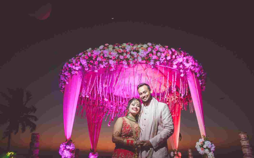 The new weds stands beneath a large, ornate floral archway.