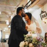 The bride smiles her heart out as her to be husband kisses on the forehead.