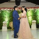 The couple smiling at each other while the elaborate floral decor behind a perfectly lit up