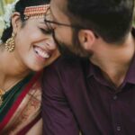 The bride's eyes are crinkled with laughter as her groom kisses her.