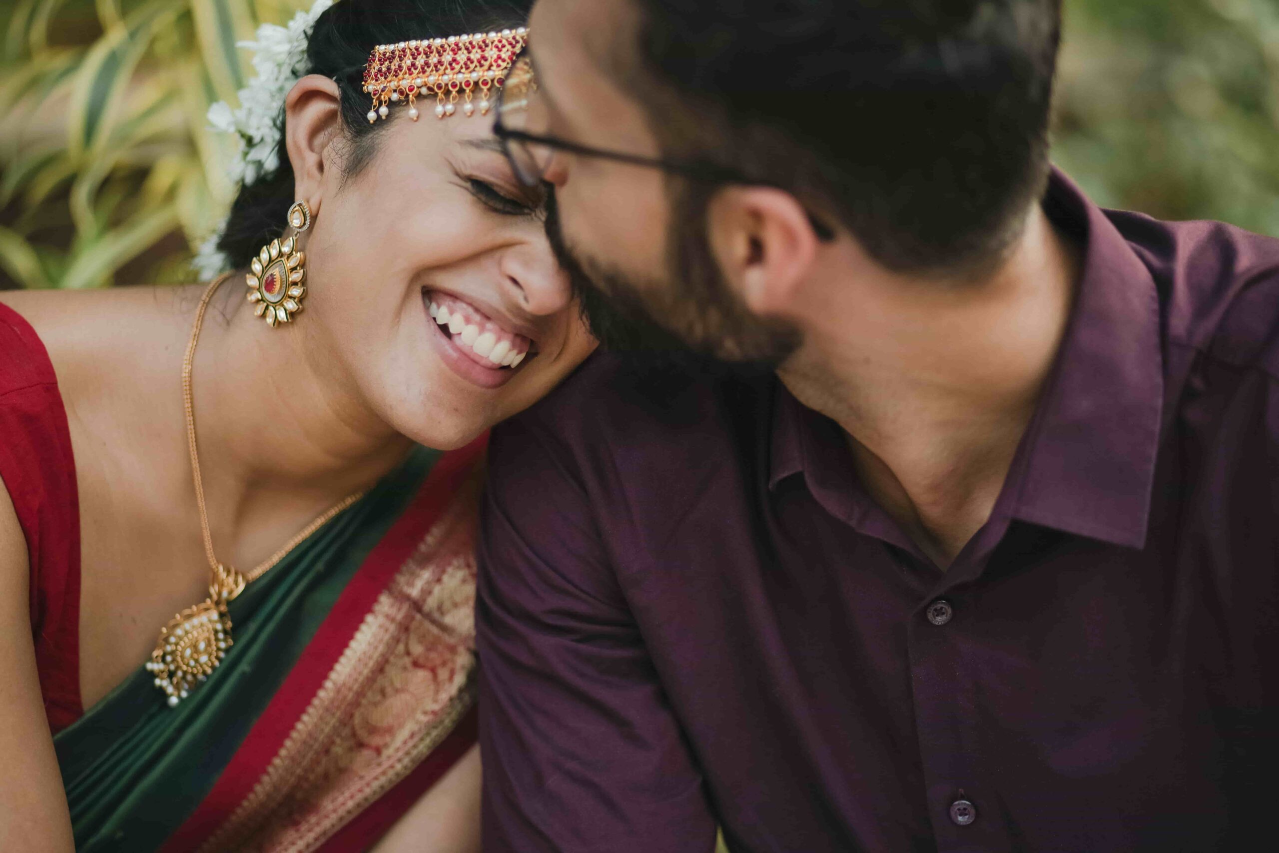 The bride's eyes are crinkled with laughter as her groom kisses her.