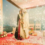 The newlyweds pose as the sparkles shine on either side of the stage.