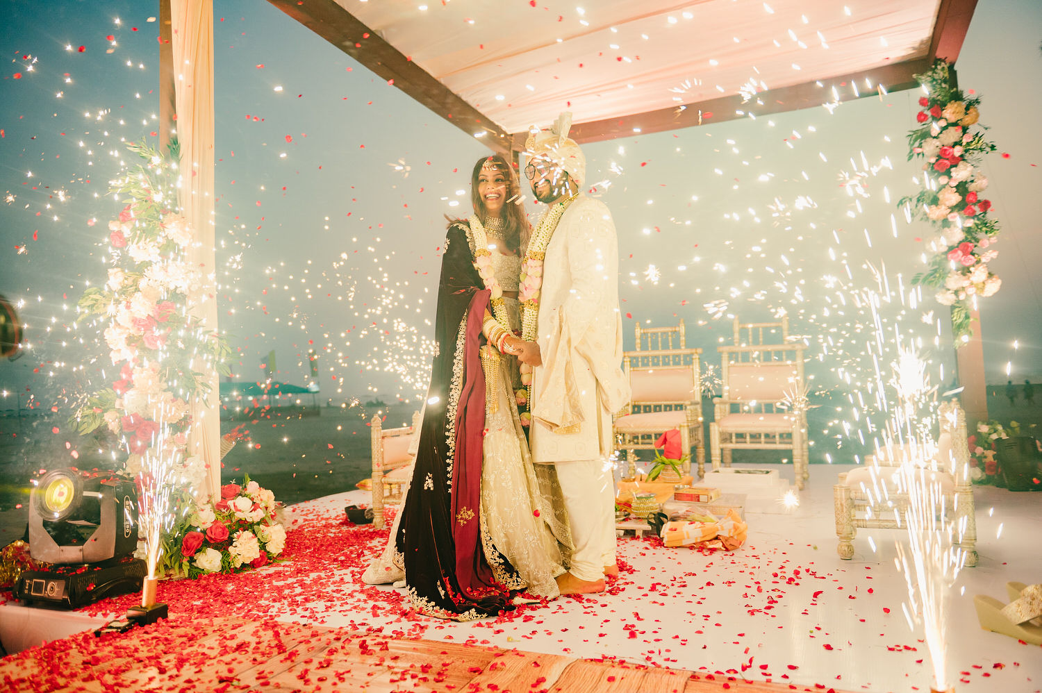 The newlyweds pose as the sparkles shine on either side of the stage.