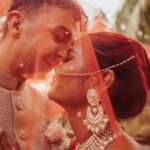 A close up photo of a couple as they pose under the bride's veil.
