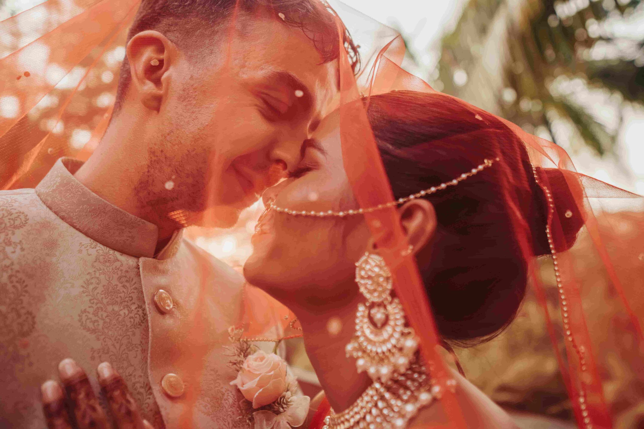 A close up photo of a couple as they pose under the bride's veil.